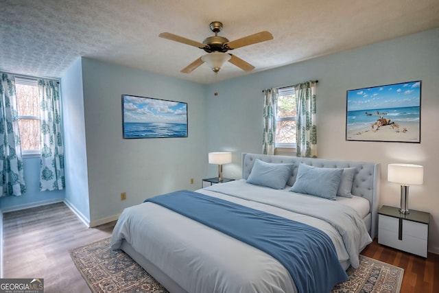 bedroom with a textured ceiling, wood finished floors, a ceiling fan, and baseboards