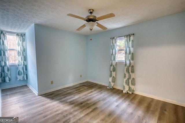 empty room featuring ceiling fan, a textured ceiling, baseboards, and wood finished floors