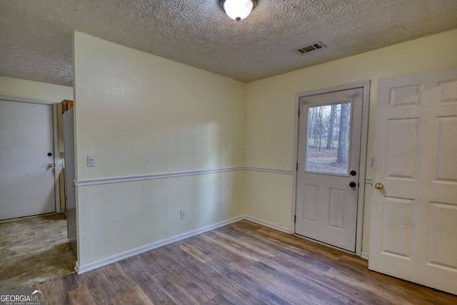 foyer entrance featuring a textured ceiling, wood finished floors, visible vents, and baseboards