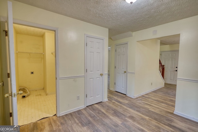 unfurnished bedroom featuring a textured ceiling, wood finished floors, and baseboards