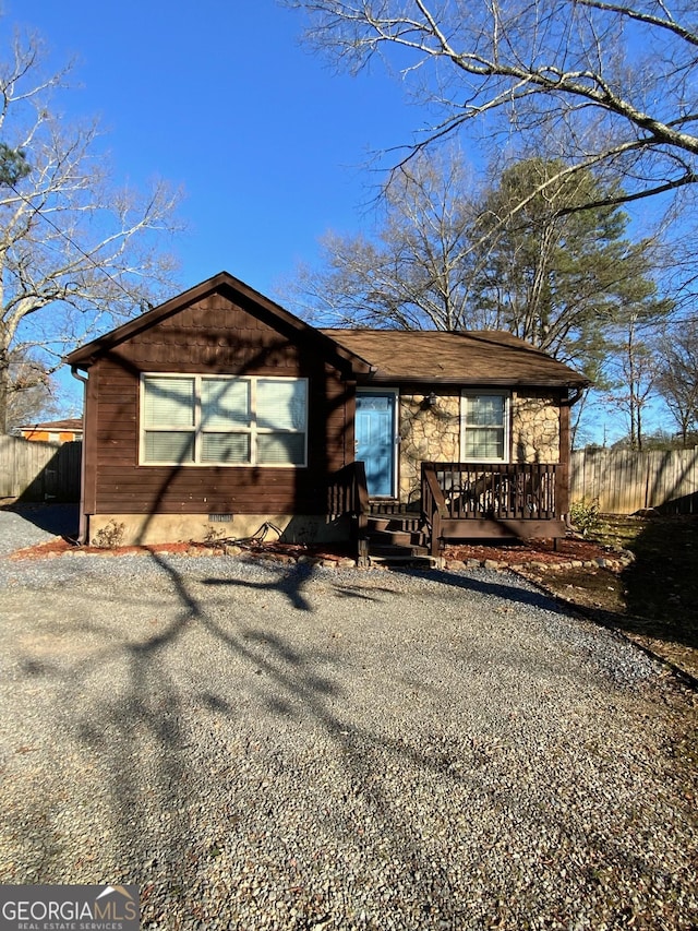 view of front of house featuring stone siding, crawl space, and fence