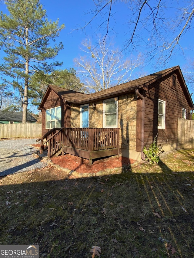 view of front of house featuring stone siding and fence