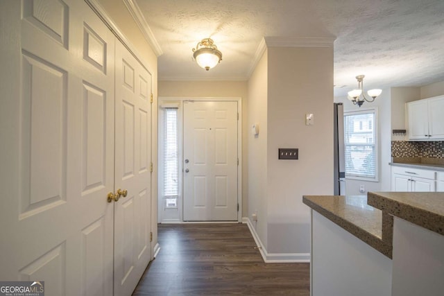 foyer entrance featuring dark wood-style floors, ornamental molding, a textured ceiling, and baseboards