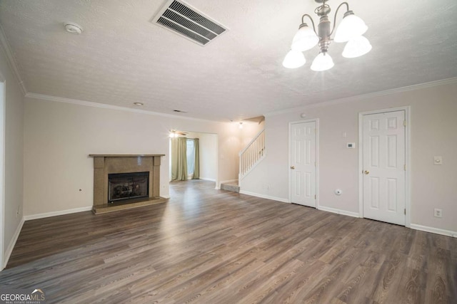 unfurnished living room with a fireplace, visible vents, a textured ceiling, wood finished floors, and stairs