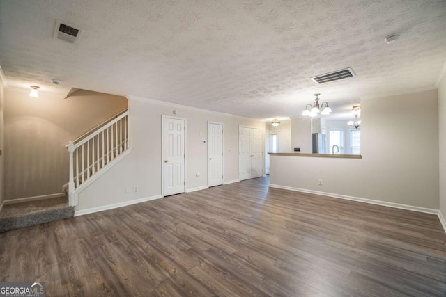 unfurnished living room featuring stairs, dark wood-type flooring, visible vents, and an inviting chandelier