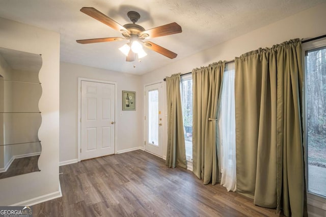 interior space with ceiling fan, dark wood-style flooring, and baseboards