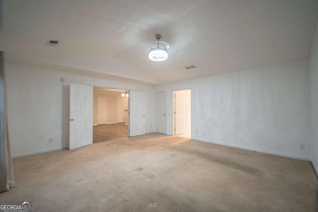 unfurnished bedroom featuring baseboards, visible vents, vaulted ceiling, and carpet flooring