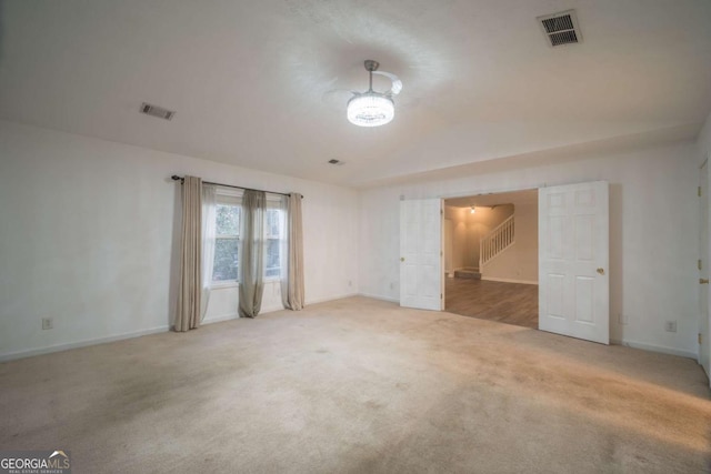 spare room with carpet, visible vents, stairway, and baseboards