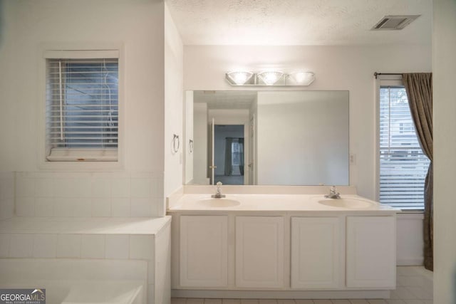 full bathroom with visible vents, a sink, and a textured ceiling