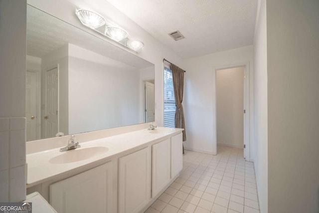 full bath with double vanity, visible vents, a sink, a textured ceiling, and tile patterned flooring