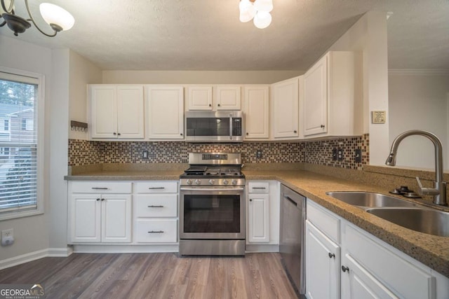 kitchen featuring appliances with stainless steel finishes, white cabinetry, a sink, and wood finished floors