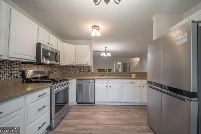 kitchen featuring white cabinetry, appliances with stainless steel finishes, backsplash, and a sink