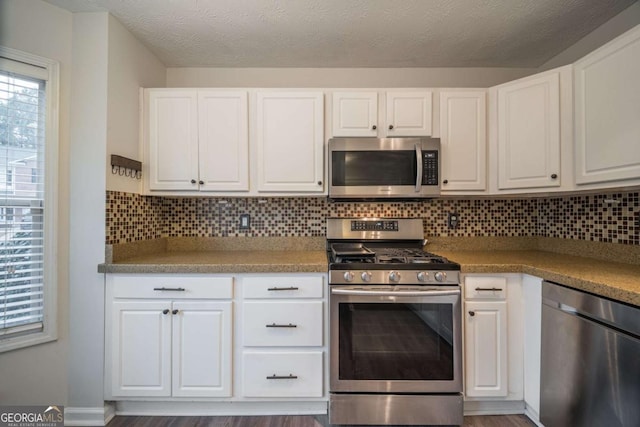 kitchen with appliances with stainless steel finishes, white cabinetry, and tasteful backsplash