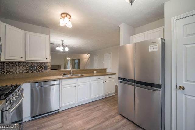 kitchen with light wood-style floors, appliances with stainless steel finishes, white cabinets, and a sink