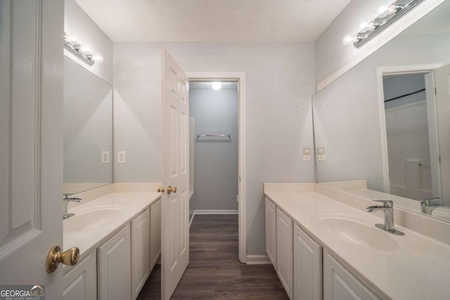 full bathroom featuring a textured ceiling, two vanities, a sink, and wood finished floors