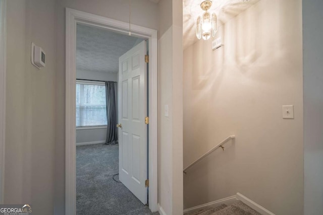 hall featuring attic access, baseboards, carpet floors, and an upstairs landing