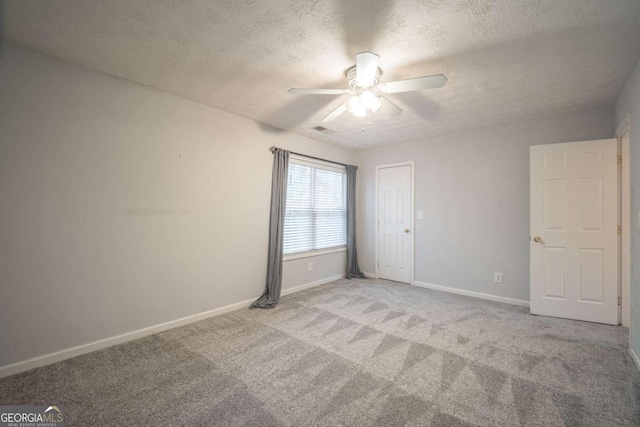 carpeted empty room featuring a textured ceiling, a ceiling fan, and baseboards