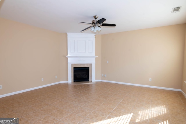 unfurnished living room featuring a large fireplace, light tile patterned floors, visible vents, baseboards, and a ceiling fan