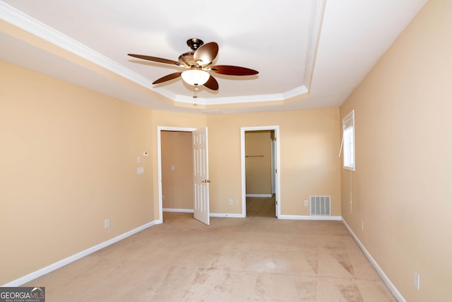 unfurnished bedroom with a tray ceiling, crown molding, visible vents, light carpet, and baseboards