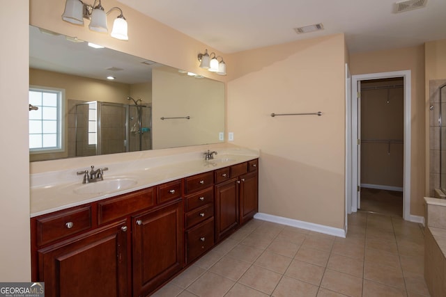 bathroom featuring double vanity, visible vents, a sink, and tiled shower