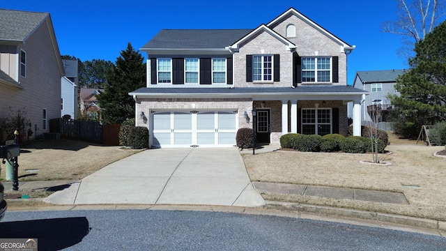 traditional-style home with a garage, concrete driveway, brick siding, and fence