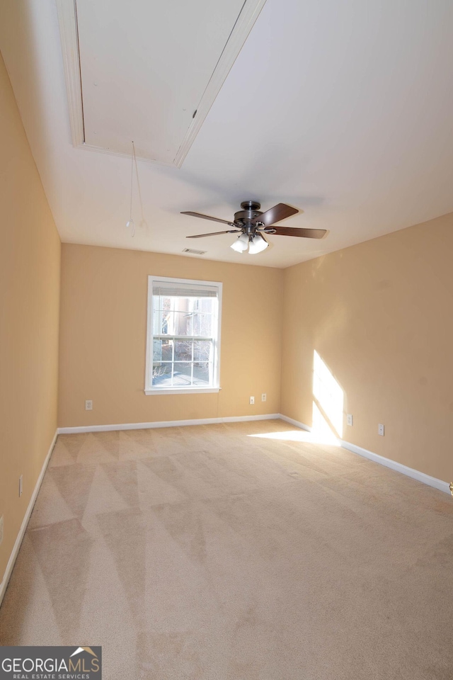 unfurnished room with baseboards, a ceiling fan, attic access, and light colored carpet