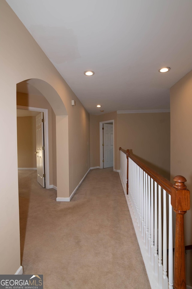 hall featuring baseboards, recessed lighting, arched walkways, and light colored carpet