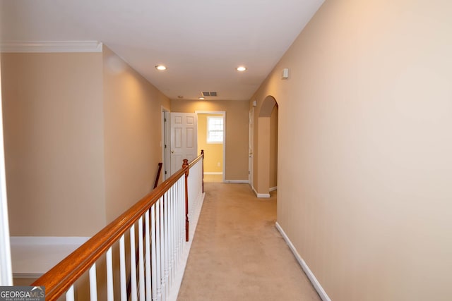 corridor featuring arched walkways, recessed lighting, light colored carpet, visible vents, and baseboards