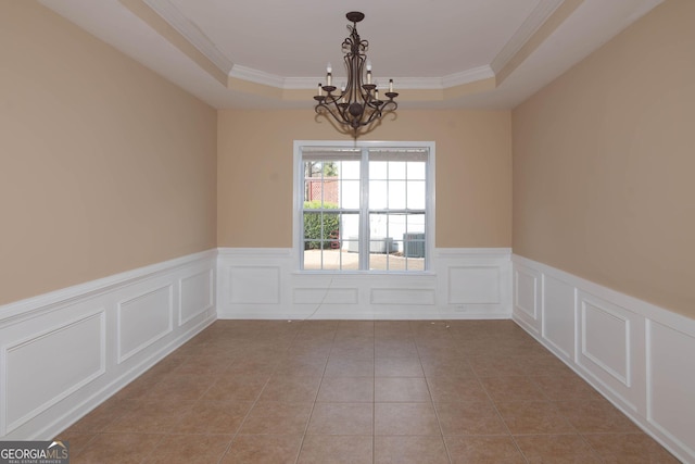 empty room with a wainscoted wall, tile patterned floors, a raised ceiling, and an inviting chandelier