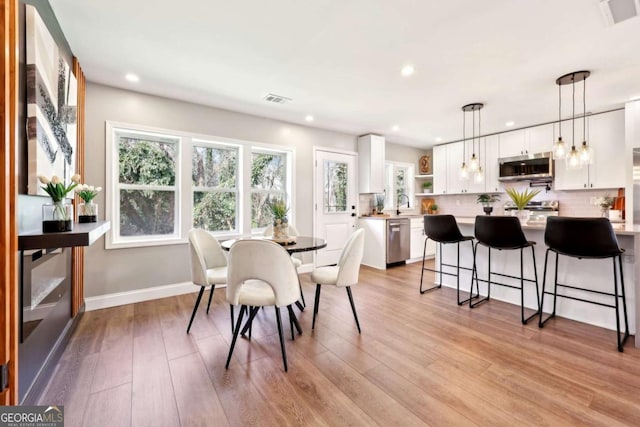 dining space with visible vents, light wood-style flooring, and baseboards