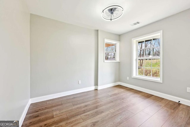 spare room featuring visible vents, baseboards, and wood finished floors