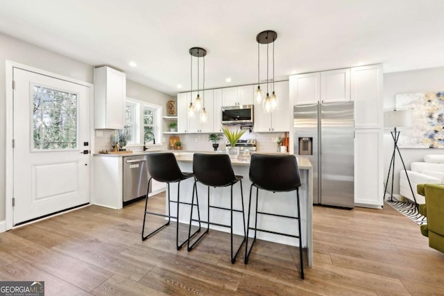 kitchen with white cabinetry, light wood-style floors, light countertops, appliances with stainless steel finishes, and open shelves