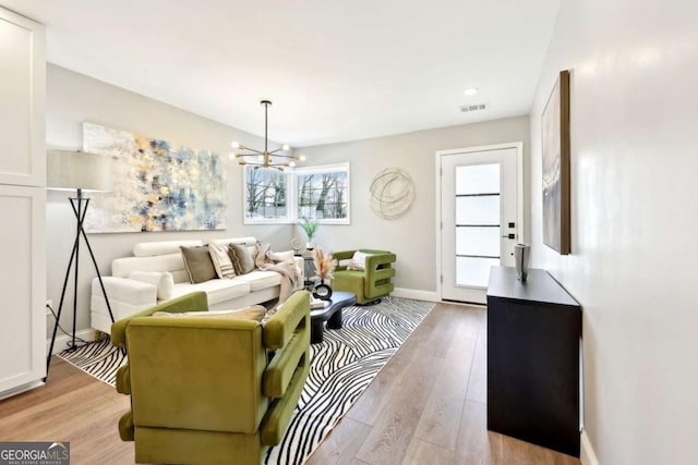 living room featuring light wood-style floors, visible vents, and baseboards