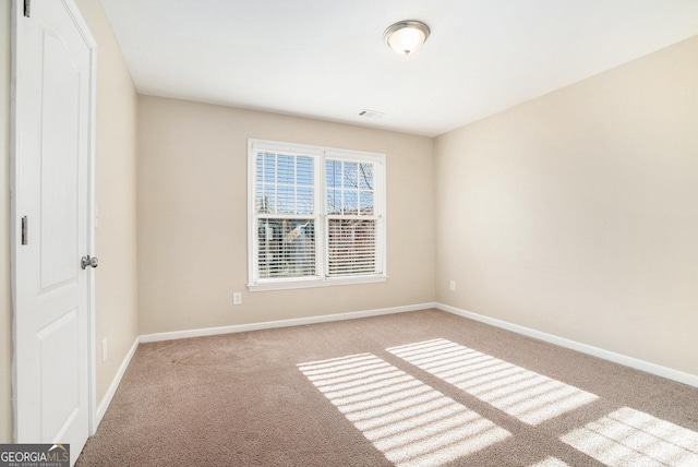 spare room featuring carpet, visible vents, and baseboards