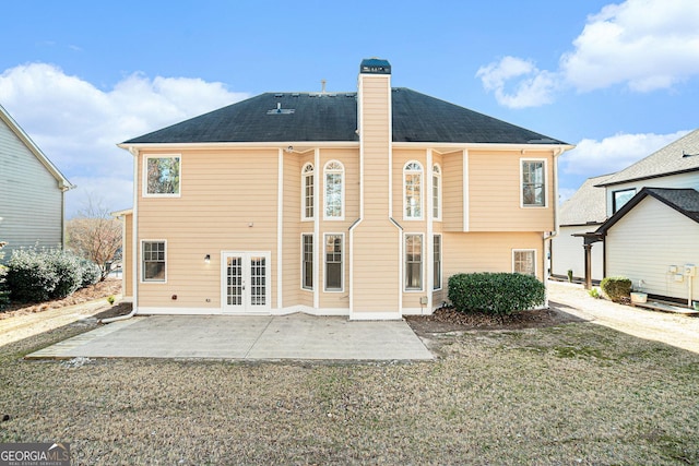 back of property featuring french doors, a patio, a chimney, and a lawn