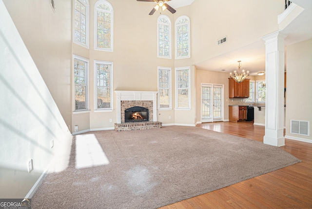 unfurnished living room featuring decorative columns, a fireplace, visible vents, and wood finished floors