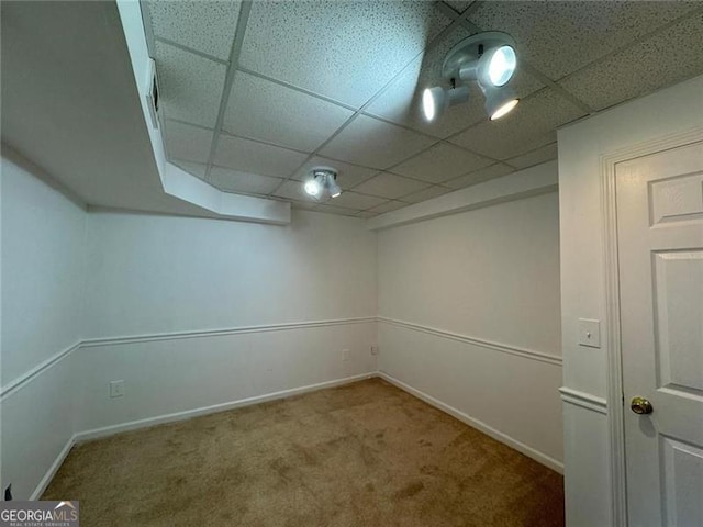 finished basement with a paneled ceiling, carpet, and baseboards