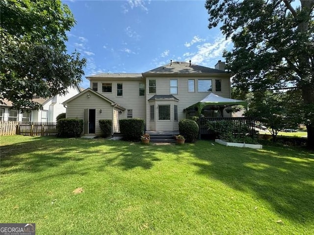 view of front of house featuring entry steps, fence, a chimney, and a front lawn