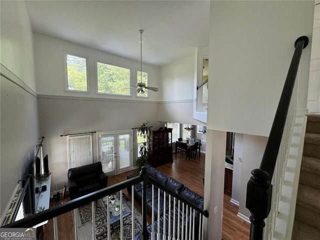 interior space with a ceiling fan, baseboards, a high ceiling, and wood finished floors