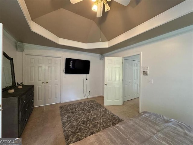 bedroom with carpet floors, a tray ceiling, vaulted ceiling, and a ceiling fan