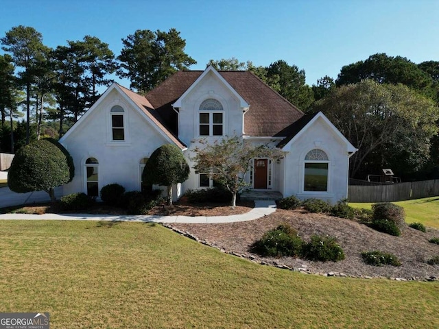 view of front of house with a front lawn, fence, and stucco siding