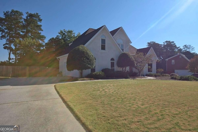 view of front facade with stucco siding, fence, and a front yard