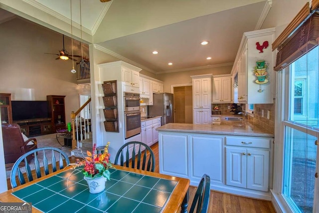 kitchen featuring wood finished floors, a sink, stainless steel appliances, crown molding, and backsplash