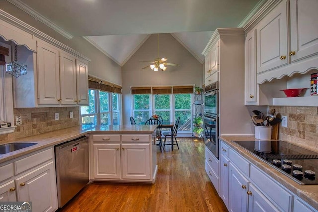 kitchen with lofted ceiling, black electric cooktop, light wood-style floors, light countertops, and stainless steel dishwasher