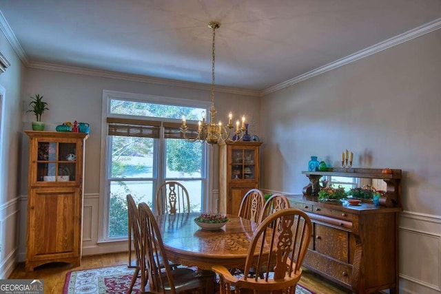 dining space with an inviting chandelier, light wood-style flooring, ornamental molding, and wainscoting