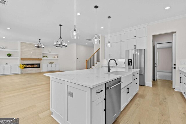 3636 Castoff Ct, Gainesville, GA 30506 - kitchen featuring appliances with stainless steel finishes, a tiled fireplace, white cabinetry, and light wood-style floors