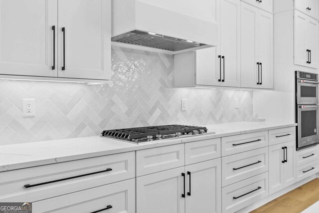 3636 Castoff Ct, Gainesville, GA 30506 - kitchen featuring decorative backsplash, custom range hood, appliances with stainless steel finishes, light stone countertops, and white cabinetry
