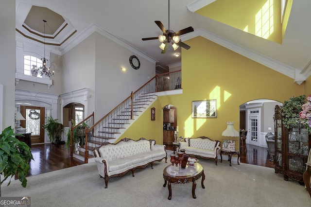 living room with a wealth of natural light, stairs, arched walkways, and crown molding