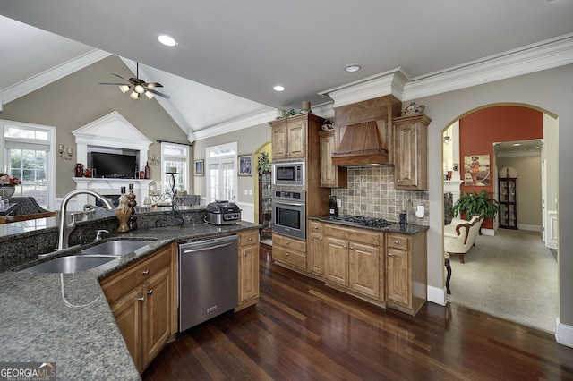 kitchen with stainless steel appliances, lofted ceiling, a sink, dark stone countertops, and premium range hood