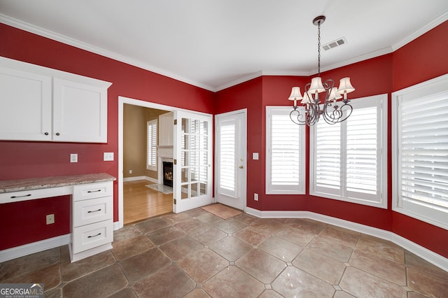 interior space with visible vents, an inviting chandelier, a fireplace with flush hearth, ornamental molding, and built in study area